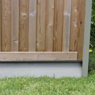 DuraPost Olive Grey gravel board shown under a wooden board fence